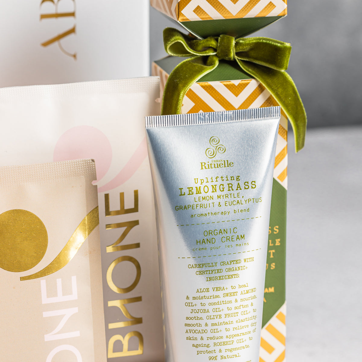 Urban Rituelle lemongrass hand cream beside a gold-patterned Christmas cracker tied with green velvet ribbon