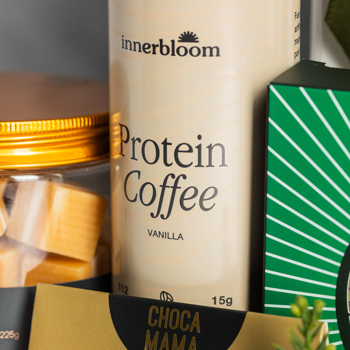 Innerbloom vanilla protein coffee beside a gold-lidded jar of Jersey caramels and green peppermint bark packaging.