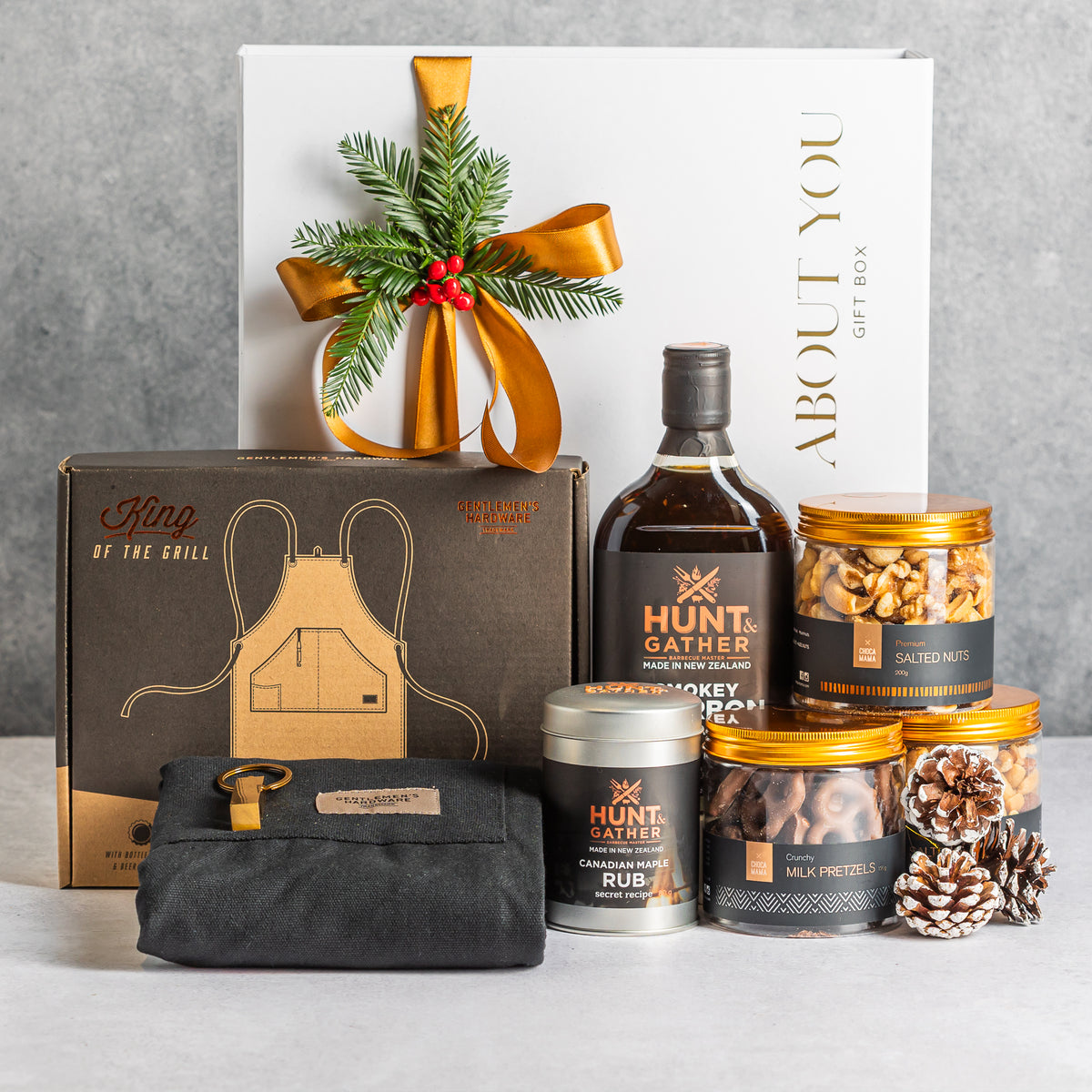 Christmas BBQ gift box with a black apron, smoky bourbon sauce, maple rub, salted nuts and chocolate-coated pretzels.