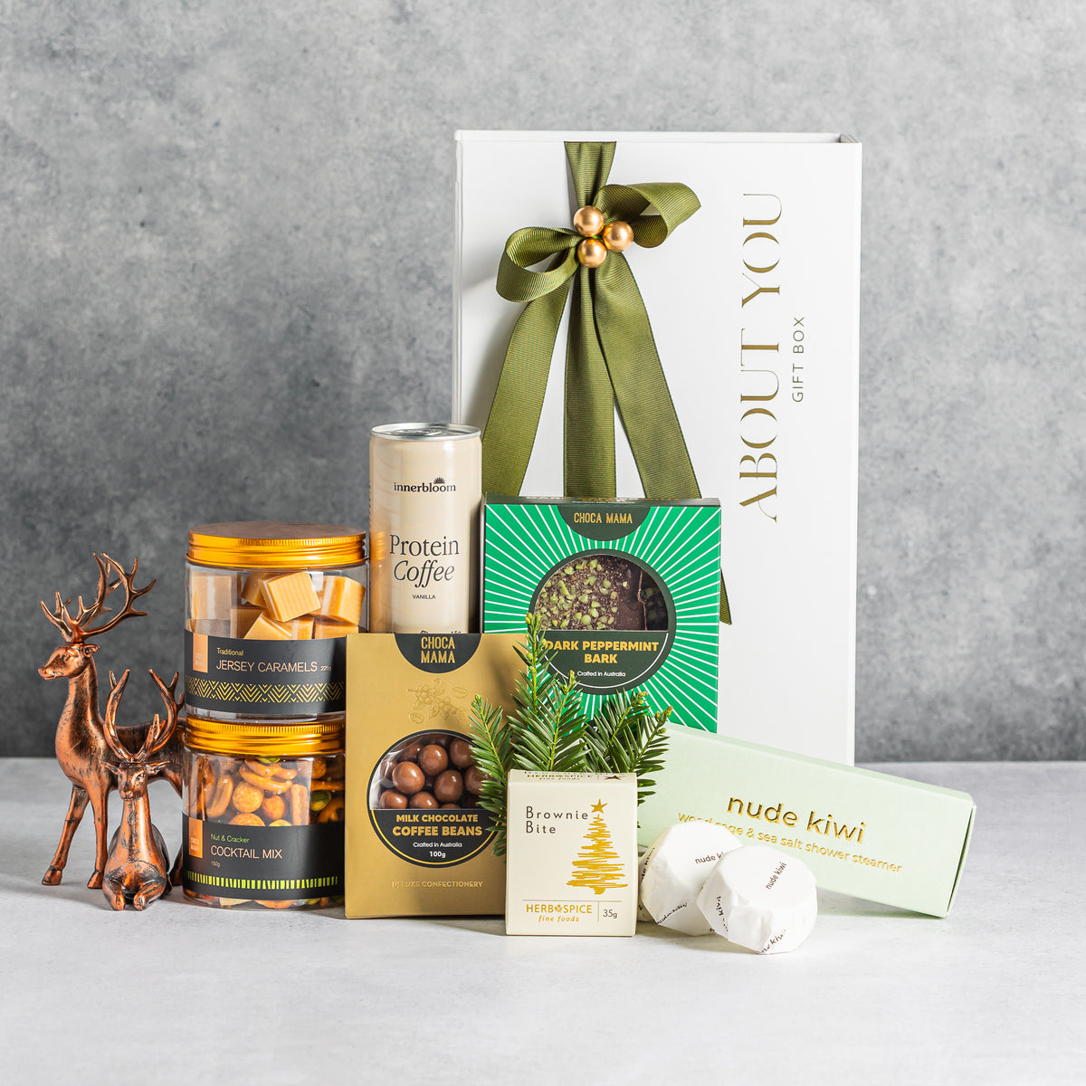 Christmas gift box with vanilla protein coffee, chocolates, caramels, snack mix, a brownie and shower steamers