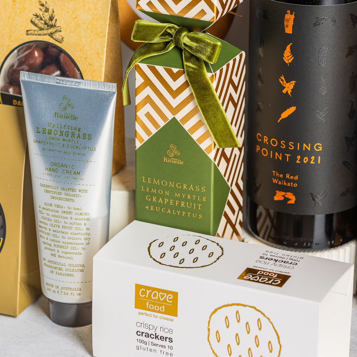 Crossing Point Waikato red wine beside lemongrass hand cream, a gold-patterned Christmas cracker and rice crackers